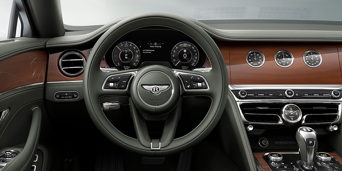 Bentley Istanbul New Bentley Flying Spur sedan front cabin in Cumbrian Green hide and Crown Cut walnut veneer showing steering wheel and Rotating Display with three clocks on face